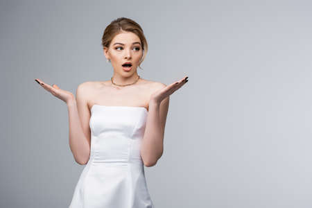 shocked bride in white wedding dress gesturing isolated on greyの写真素材