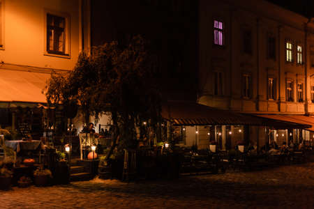 LVIV, UKRAINE - OCTOBER 23, 2019: people sitting in cafe with terrace in evening