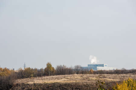 LVIV, UKRAINE - OCTOBER 23, 2019: smoke near factory with cersanit lettering and green trees against skyのeditorial素材
