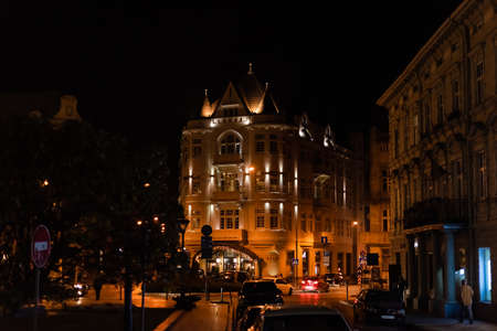 LVIV, UKRAINE - OCTOBER 23, 2019: buildings with lighting near road with cars at night