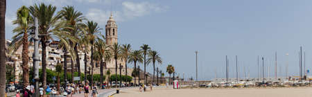 BARCELONA, SPAIN - APRIL 30, 2020: People on urban street with palm trees and Church of Saint Bartolomeus and Santa Tecla at background, panoramic cropのeditorial素材