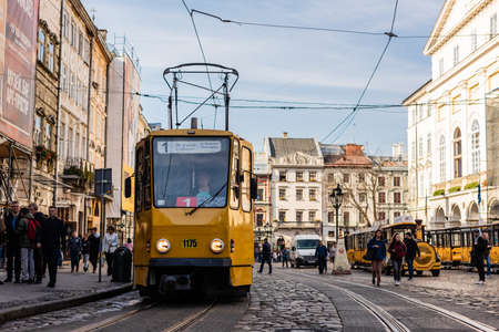 LVIV, UKRAINE - OCTOBER 23, 2019: tram with route number one lettering and people walking along street in city centerのeditorial素材