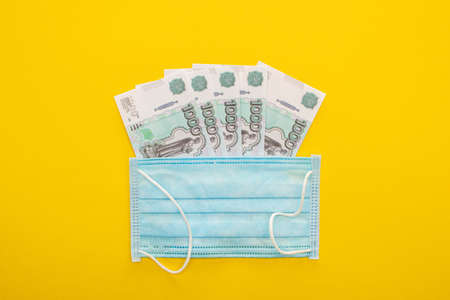 top view of Russian banknotes and medical mask on yellow backgroundのeditorial素材