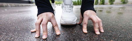 horizontal crop of runner in white sneakers standing in starting pose outside
