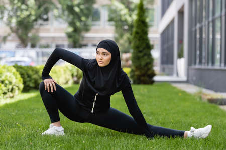attractive muslim girl stretching on green grass outsideの写真素材