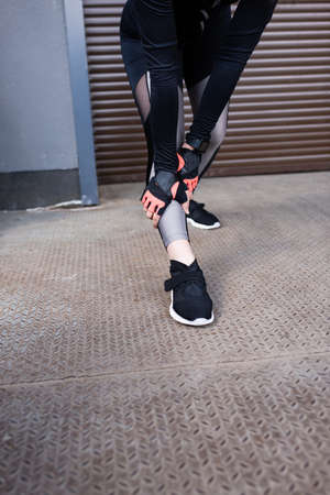 cropped view of young sportswoman touching leggings