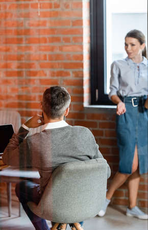 back view of businessman sitting near attractive businesswoman in officeの写真素材