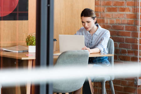selective focus of businesswoman using laptop in modern office