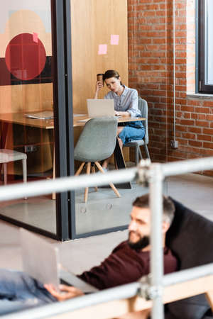 selective focus of businesswoman using laptop near businessman in modern office