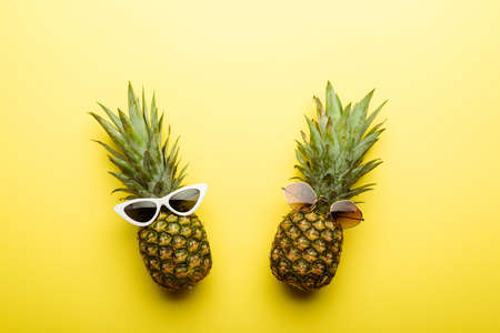 top view of ripe pineapples in sunglasses on yellow backgroundの写真素材