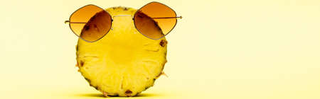 delicious sweet cut pineapple in sunglasses on yellow background, panoramic shotの写真素材