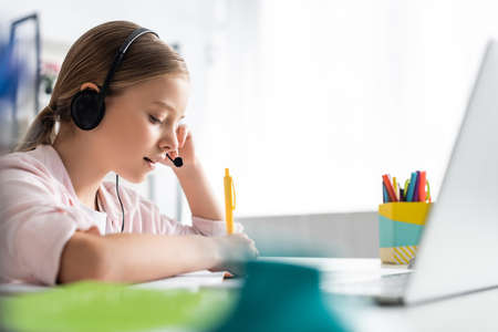 Selective focus of kid using headset during electronic learning at homeの写真素材