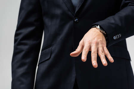 cropped view of businessman in suit manipulating with hand isolated on grayの写真素材