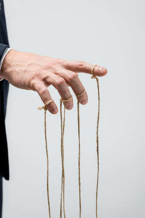 partial view of puppeteer with strings on fingers isolated on gray