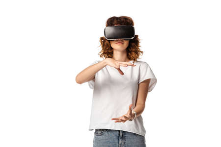 curly young woman in virtual reality headset gesturing isolated on white