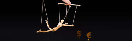 cropped view of puppeteer holding wooden marionette on strings near currency signs isolated on...