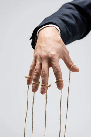 partial view of puppeteer with strings on fingers isolated on gray