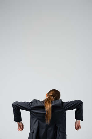 back view of businesswoman marionette in suit posing isolated on gray