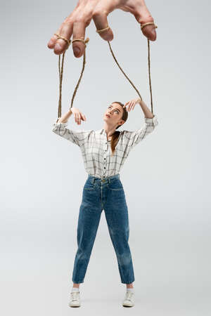 cropped view of puppeteer holding marionette on strings isolated on gray