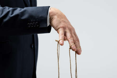 cropped view of puppeteer with strings on fingers isolated on gray