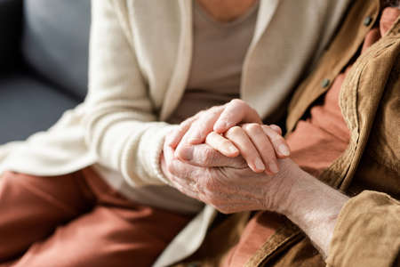 partial view of senior couple holding hands, selective focusの写真素材