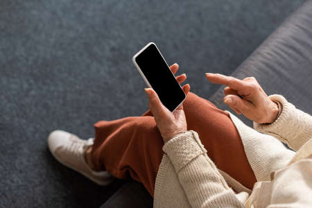 high angle view of senior woman holding smartphone with blank screen