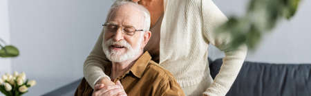 cropped view of woman embracing happy senior husband, panoramic cropの写真素材
