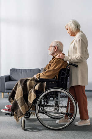 side view of senior woman touching shoulder of handicapped husband, sick on dementiaの写真素材