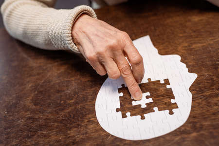 partial view of woman combing jigsaw puzzle as dementia therapyの写真素材