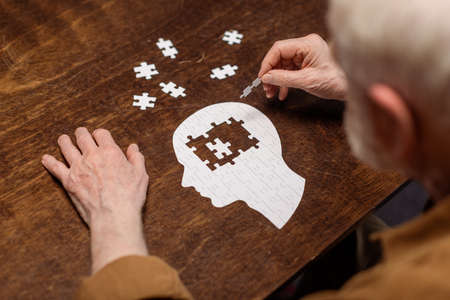 high angle view of senior man collecting jigsaw puzzle as dementia rehabの素材 [FY310151568563]