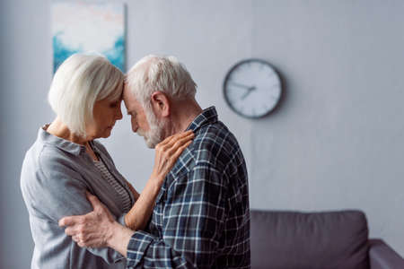 senior woman and husband with dementia hugging while standing face to face
