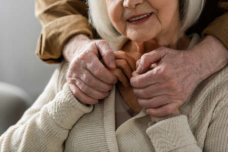 partial view of senior man holding hands of smiling wifeの写真素材
