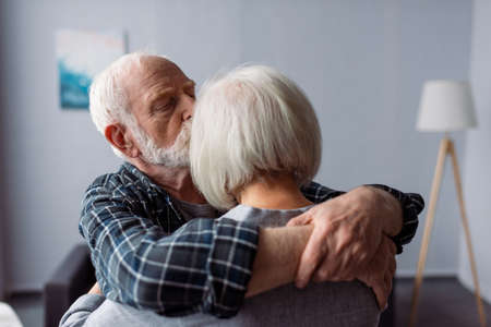 senior man hugging and kissing wife, suffering from alzheimer diseaseの写真素材