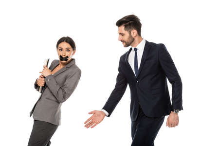 bearded businessman in formal wear molesting businesswoman with duct tape on mouth isolated on white, sexual harassment conceptの写真素材