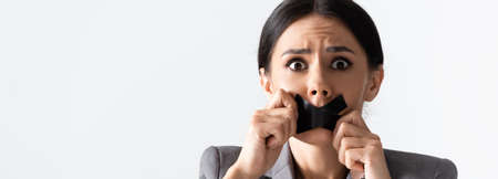 panoramic crop of scared businesswoman touching  mouth isolated on white, gender inequality conceptの写真素材