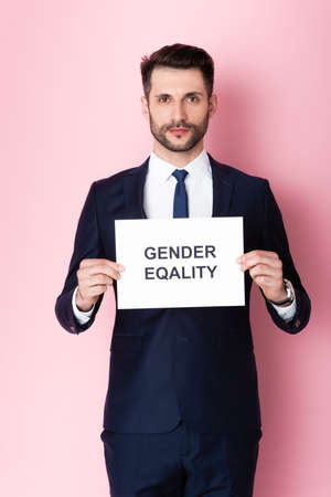 businessman holding placard with gender equality lettering on pinkの写真素材