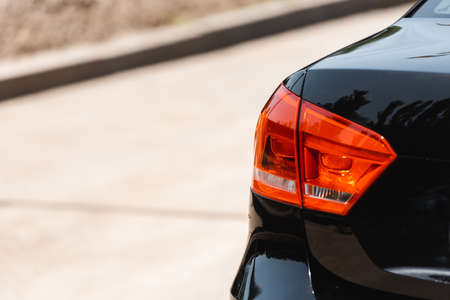 Back headlights of black car on urban street