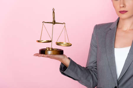 cropped view of businesswoman in suit holding golden scales on pink, gender equality conceptの写真素材