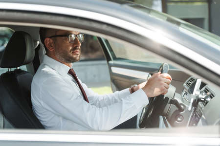 Side view of handsome businessman driving car