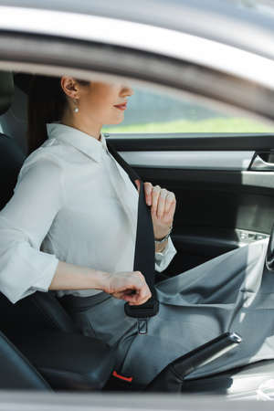 Cropped view of businesswoman holding seat belt while sitting in autoの写真素材