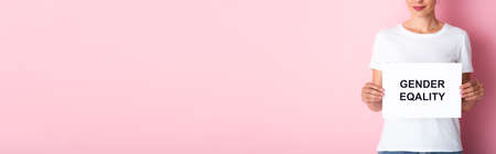 panoramic crop of woman in white t-shirt holding placard with gender equality lettering on pink