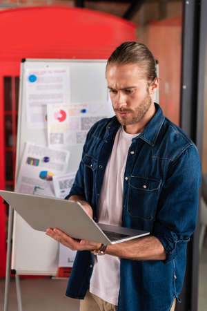 handsome businessman using laptop near charts and graphs