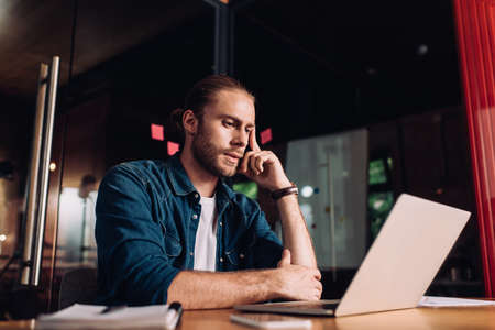 selective focus of pensive businessman looking at laptop in officeの写真素材
