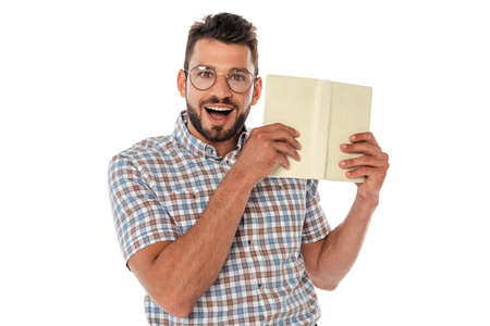 Cheerful nerd in eyeglasses holding open book isolated on whiteの写真素材