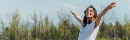 horizontal crop of cheerful woman with outstretched hands smiling outsideの写真素材