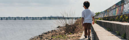 horizontal concept of boy walking near river