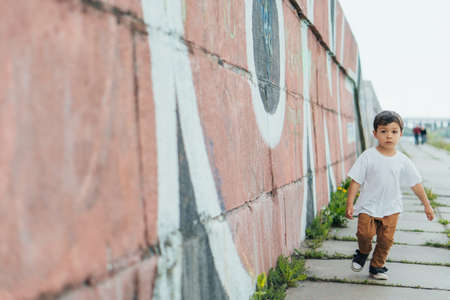 selective focus of cute boy running near wall with graffitiの写真素材