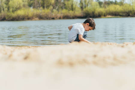 selective focus of cute boy sitting near pondの写真素材