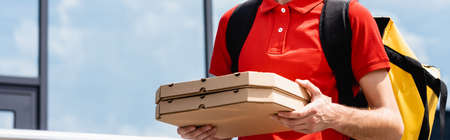 Panoramic crop of courier holding pizza boxes on urban streetの写真素材