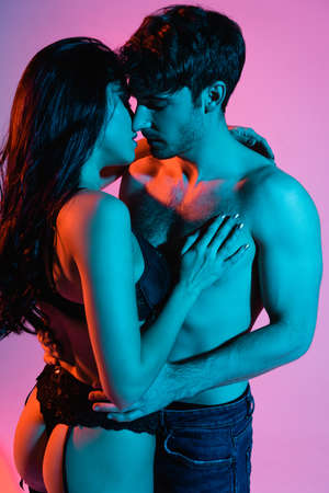 blue lighting on young and sexy couple hugging on pinkの写真素材